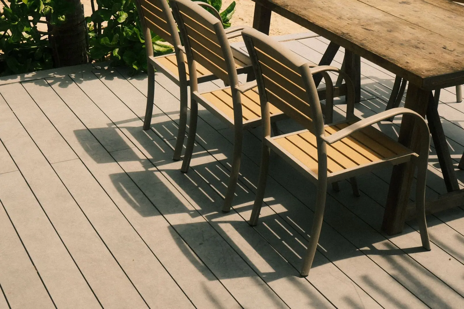 Clean wooden deck with patio chairs and a table in the sun