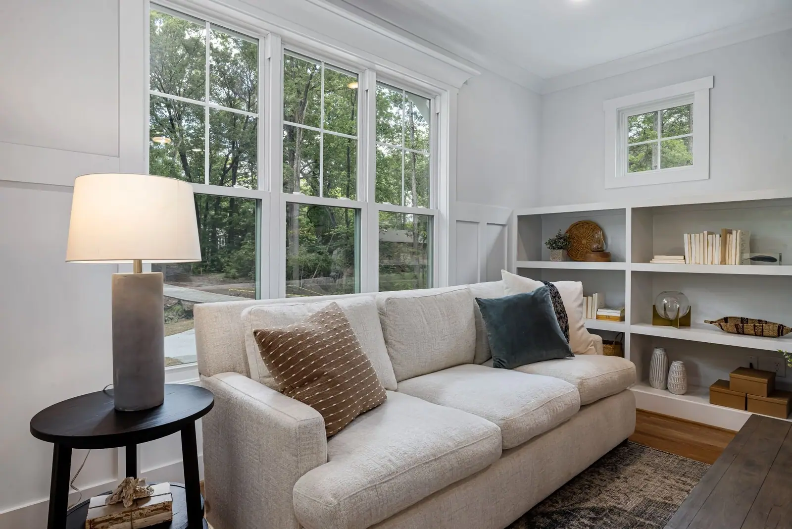 Bright, tidy living room with a sofa, built-in shelves and large windows