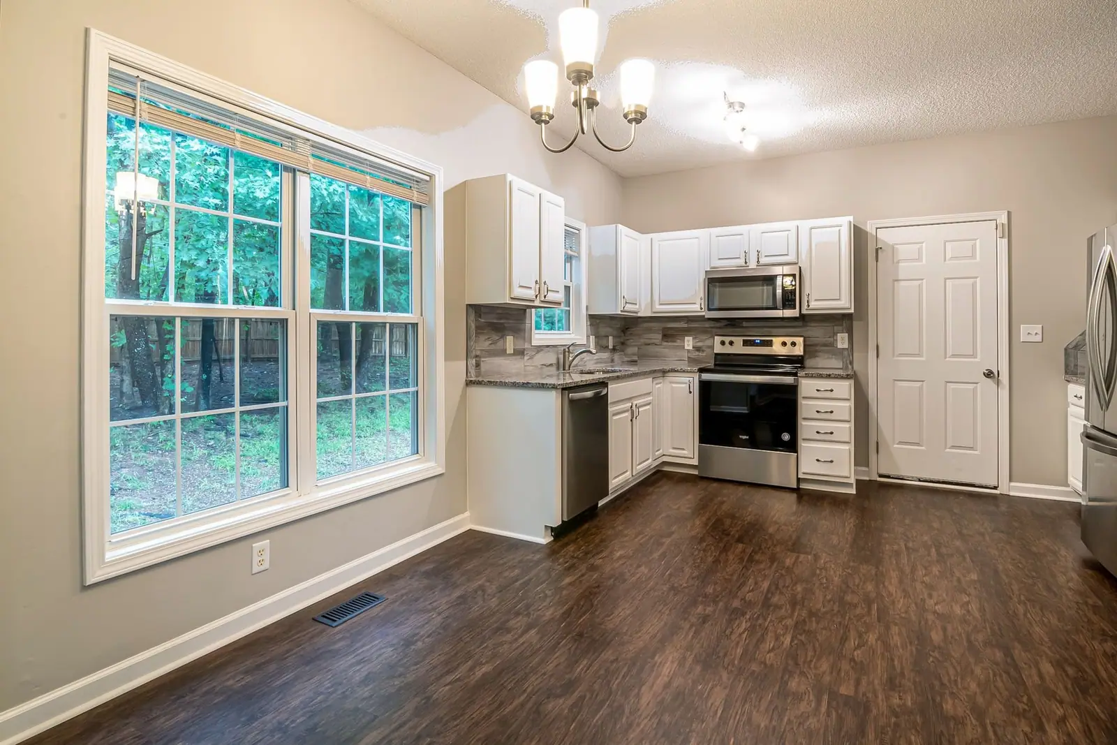 Kitchen with white cabinets, stainless appliances and a large window