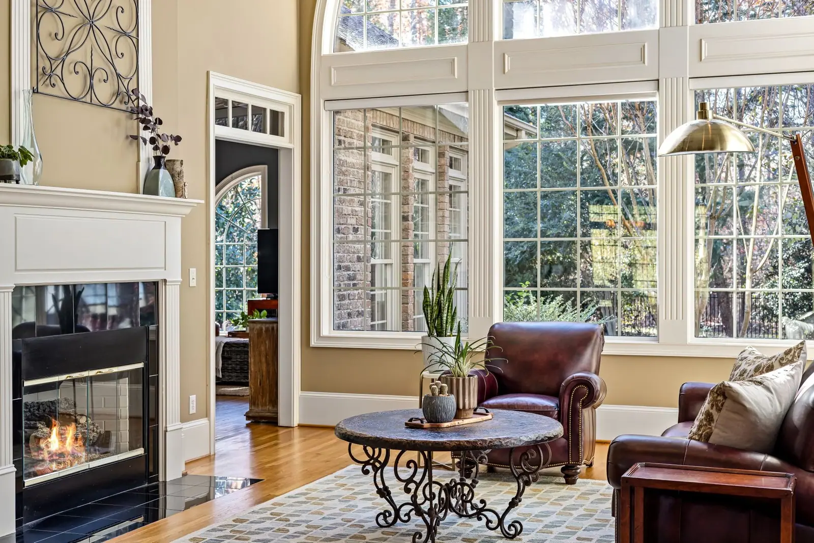 Sunny living room with a fireplace, leather chairs and tall windows