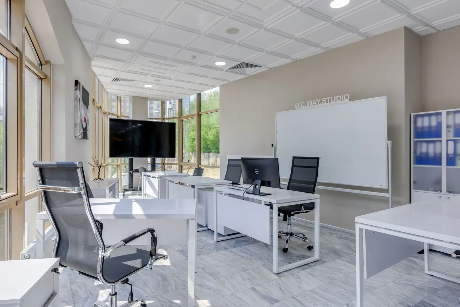 Bright office with white desks, task chairs and a whiteboard