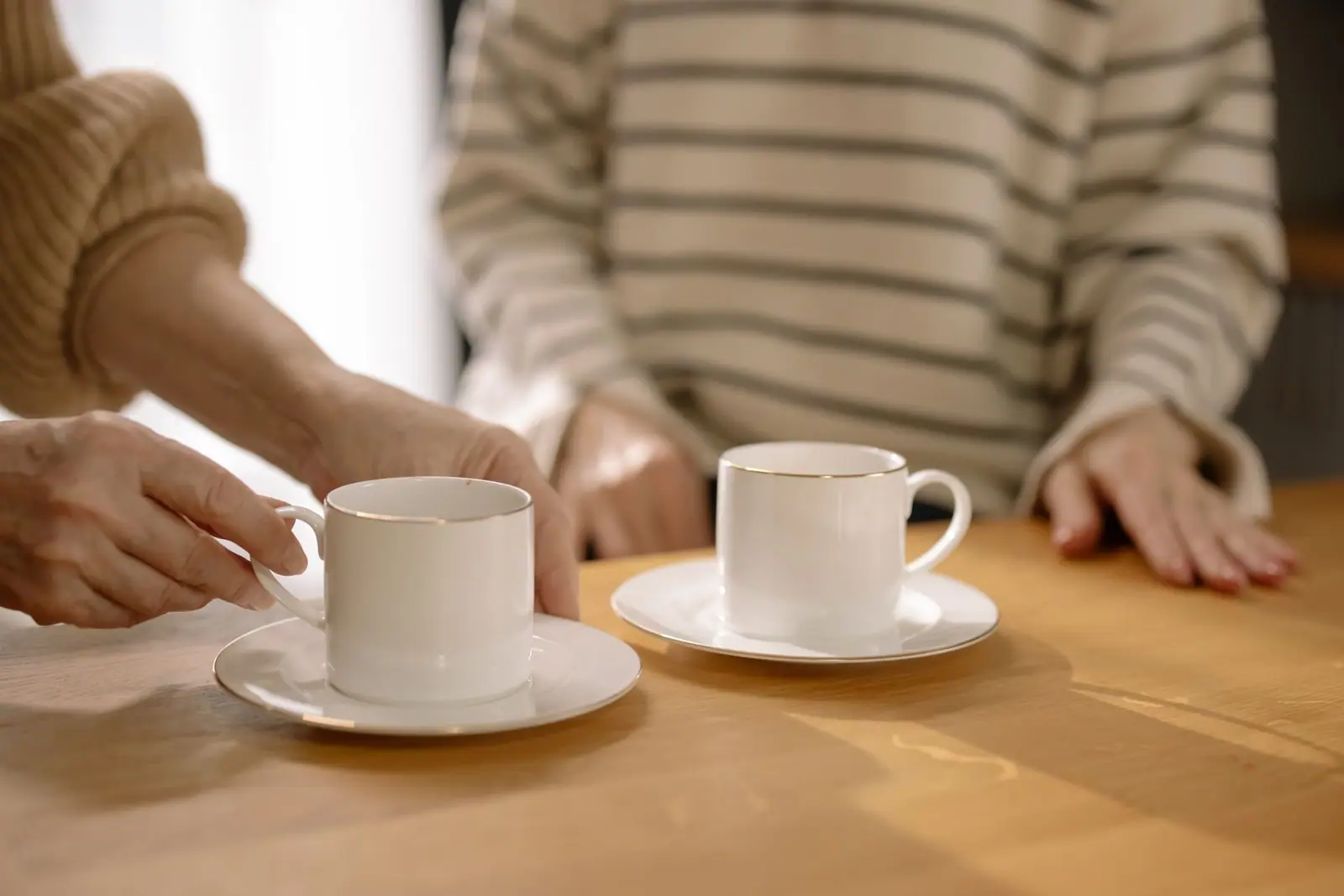 Two people with cups of coffee at a wooden table