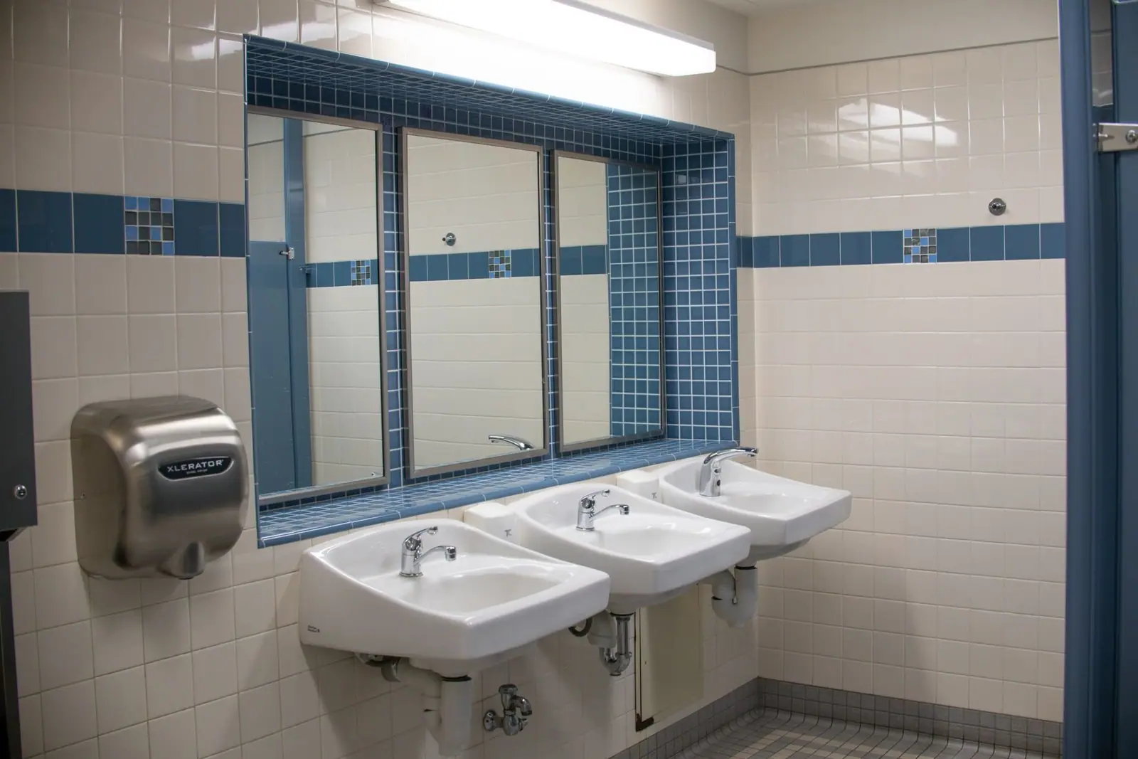Commercial restroom with three sinks, mirrors and a hand dryer