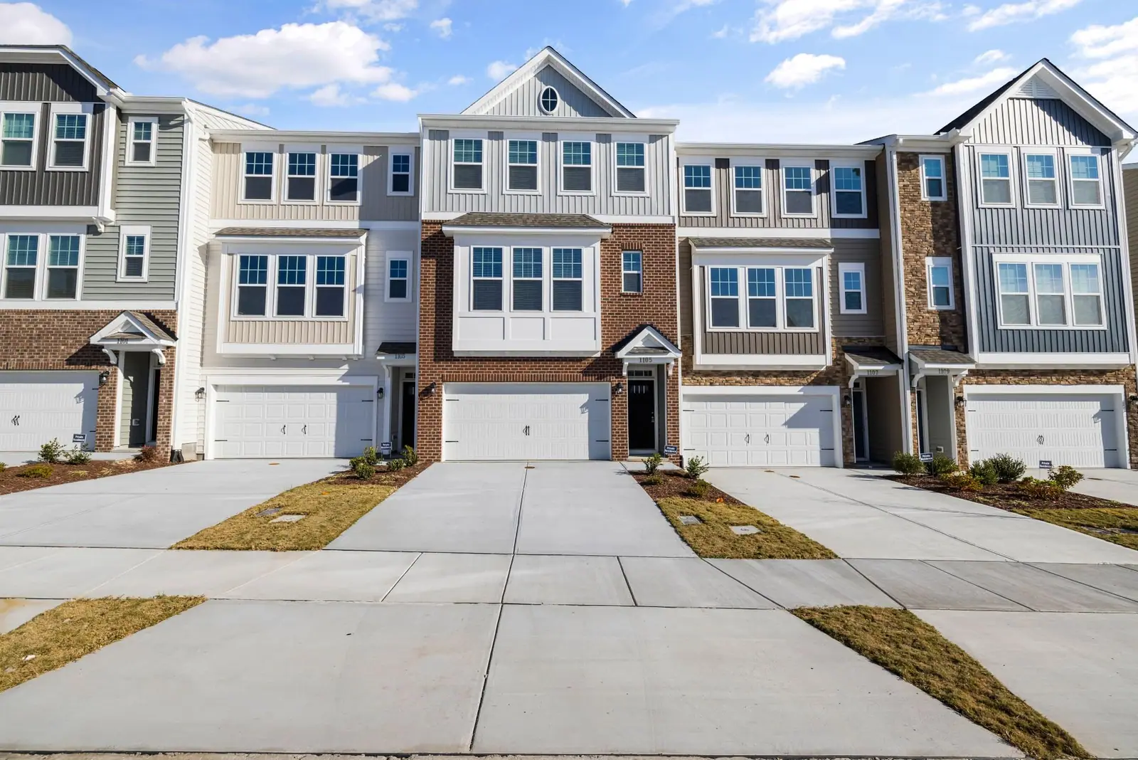 Row of townhomes with garages and driveways on a sunny day